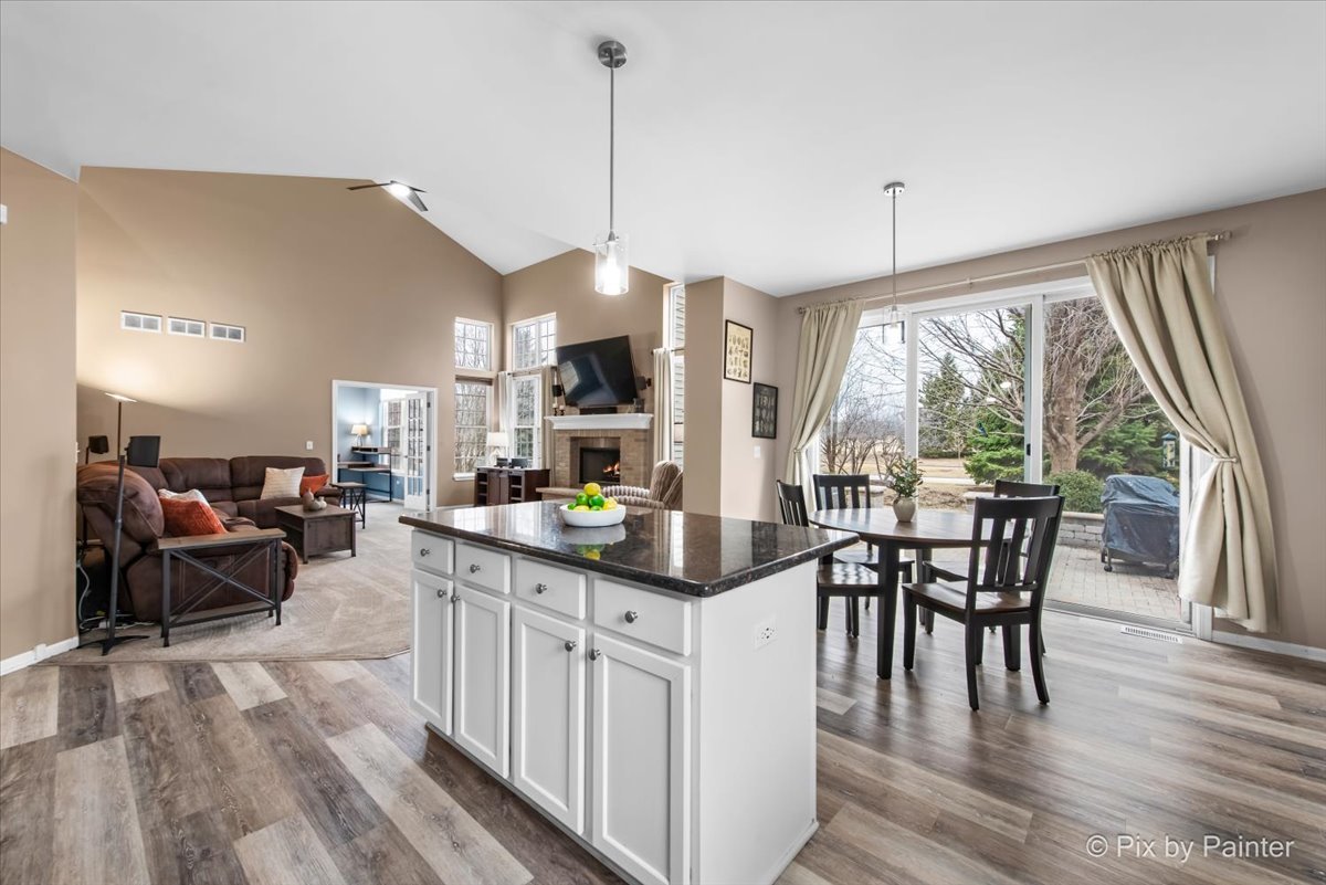 26428 Rustling Birch Way Plainfield, IL 60585 - Photo 5 of 49 a open kitchen with stainless steel appliances granite countertop a stove top oven a dining table and chairs with wooden floor