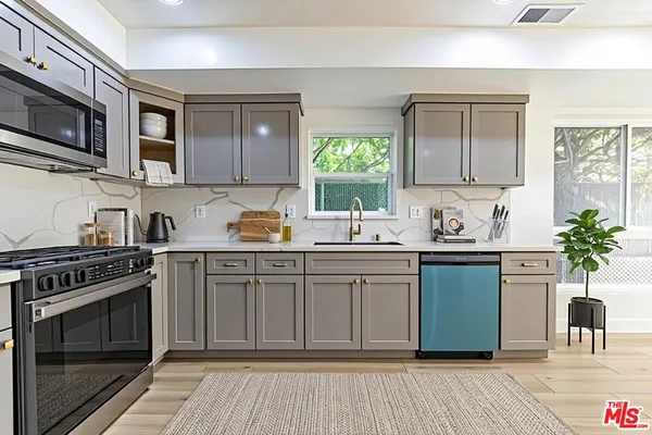 a kitchen with stainless steel appliances granite countertop a stove a sink dishwasher and microwave oven with cabinets
