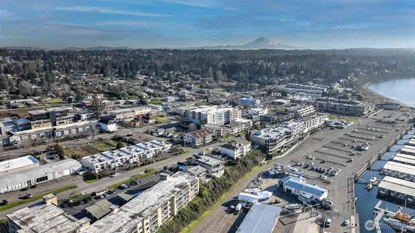 an aerial view of a city with lots of residential buildings ocean and mountain view in back