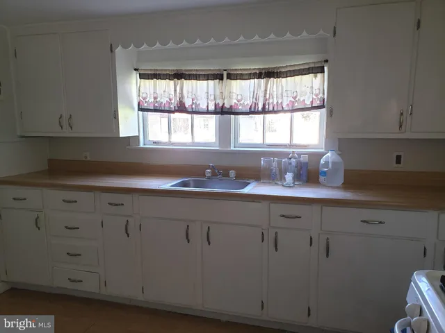 a kitchen with granite countertop white cabinets window and a sink