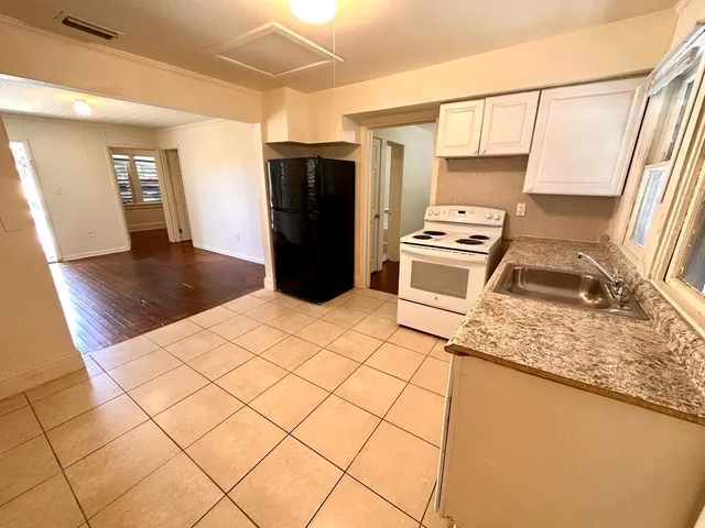 a kitchen with stainless steel appliances granite countertop a refrigerator a stove and a sink with wooden floors