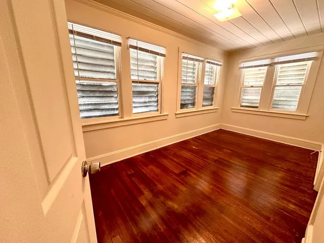 a view of an empty room with a window and wooden floor