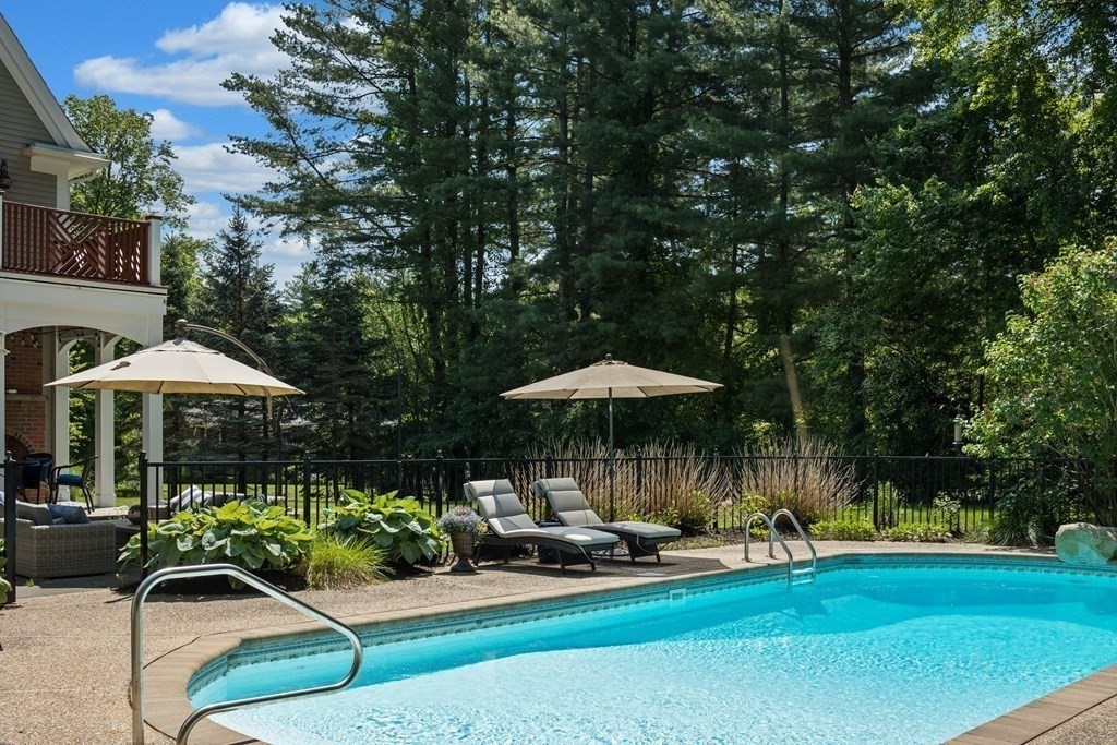 19 Marked Tree Road Sudbury, MA 01776 - Photo 37 of 42 a view of a swimming pool with lawn chairs under an umbrella