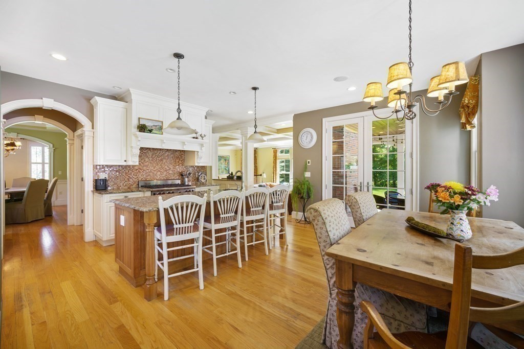 19 Marked Tree Road Sudbury, MA 01776 - Photo 7 of 42 a kitchen with stainless steel appliances granite countertop a stove a refrigerator a kitchen island with a dining table and chairs