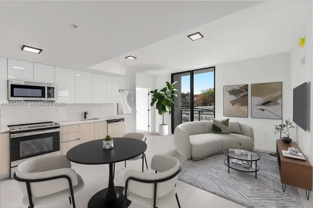a living room with furniture a rug potted plant and a view of kitchen