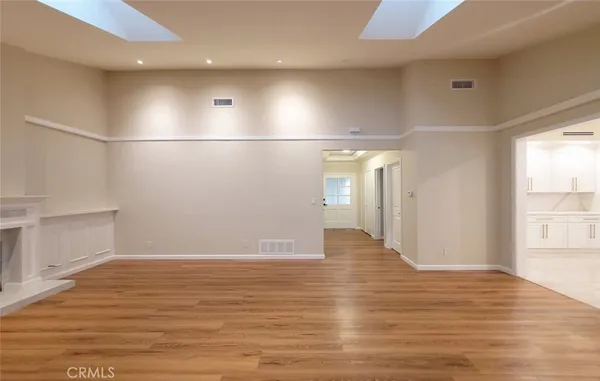 a view of an empty room with wooden floor and windows