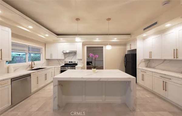 a large white kitchen with kitchen island a sink a stove a dining table and chairs