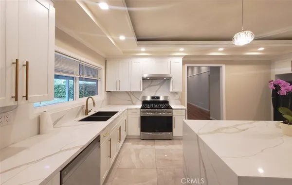 a kitchen with stainless steel appliances granite countertop a sink a stove and a refrigerator