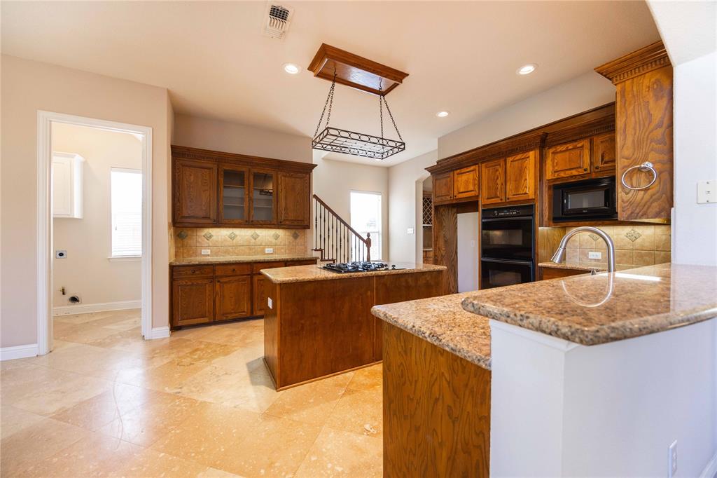 2009 Briarbrook Lane Allen, TX 75002 - Photo 11 of 40 a kitchen with stainless steel appliances granite countertop a sink refrigerator and cabinets