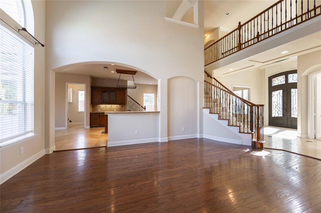 2009 Briarbrook Lane Allen, TX 75002 - Photo 13 of 40 Unfurnished living room with arched walkways, dark wood-style flooring, stairway, french doors, and a high ceiling