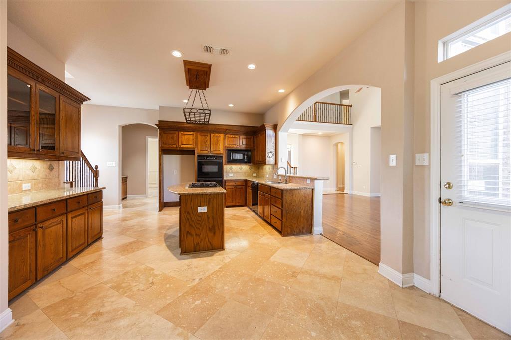 2009 Briarbrook Lane Allen, TX 75002 - Photo 9 of 40 Kitchen with arched walkways, tasteful backsplash, light stone counters, brown cabinets, and recessed lighting
