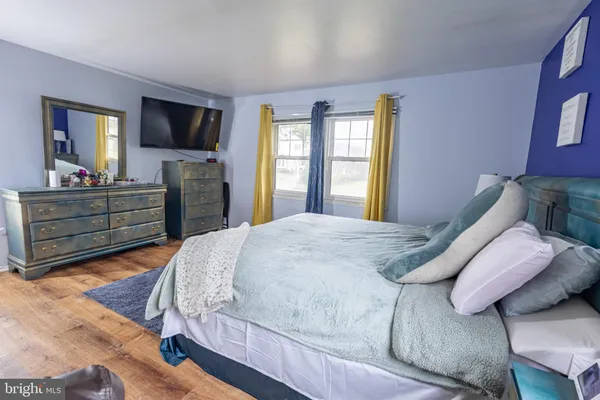 a spacious bedroom with a bed and wooden floor