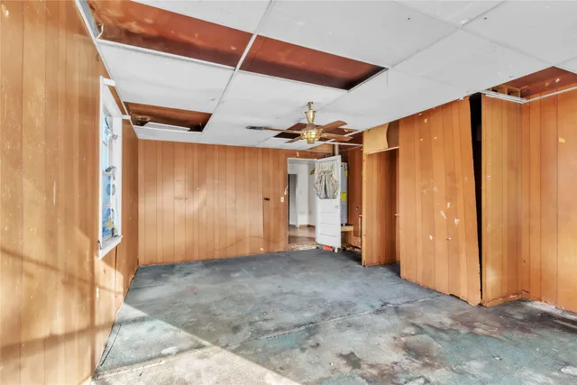 an empty room with a chandelier fan and windows