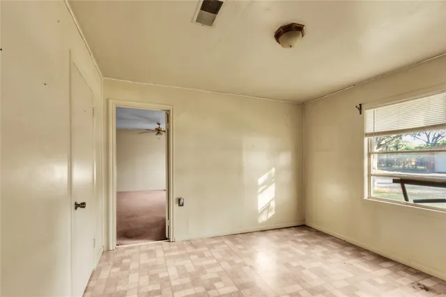 a view of an empty room with a ceiling fan and window