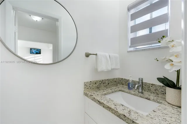 a bathroom with a granite countertop sink and a mirror