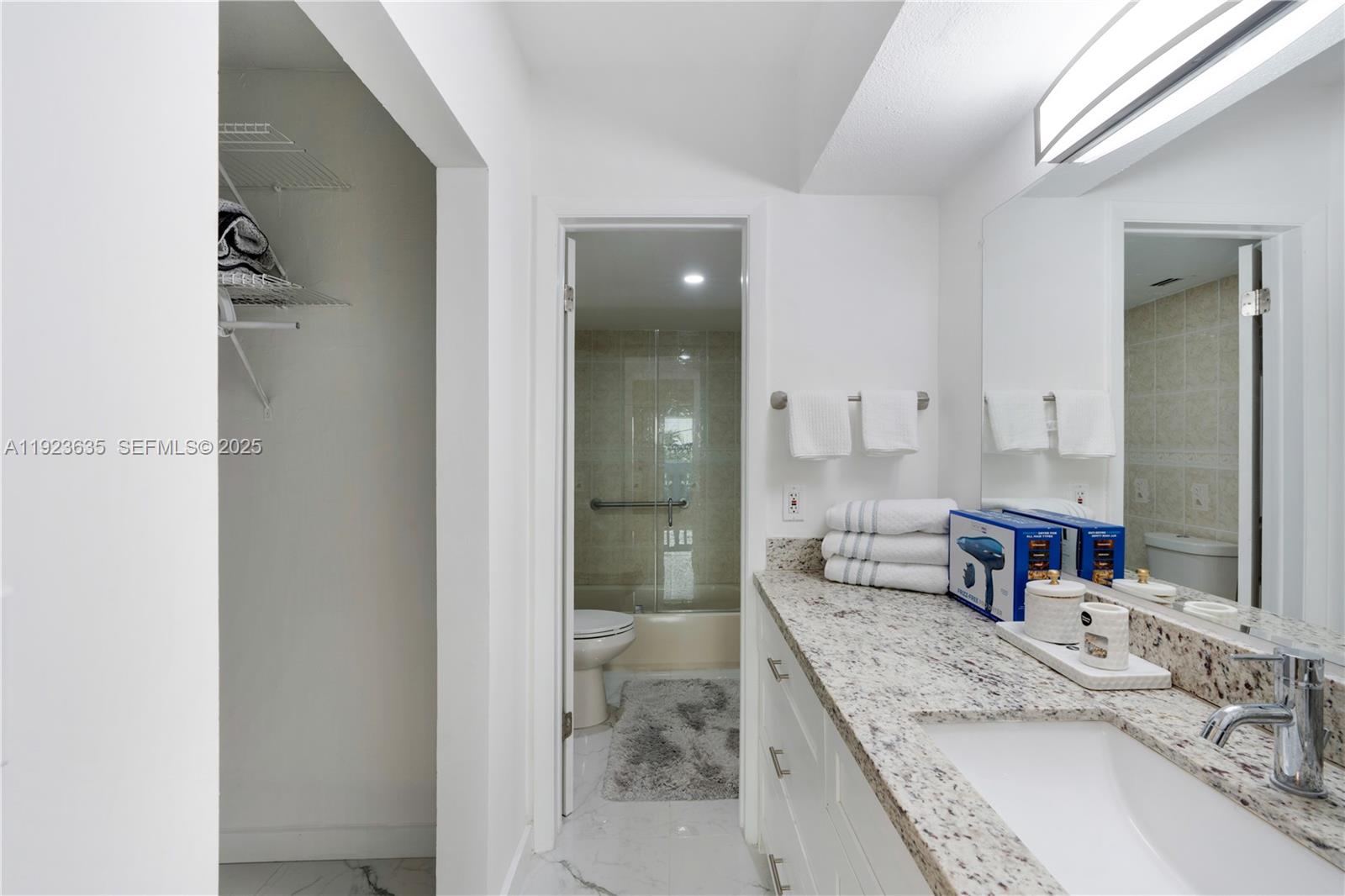 9167 Harding Avenue, Unit 9167 Surfside, FL 33154 - Photo 15 of 45 a bathroom with a granite countertop sink a mirror and a shower