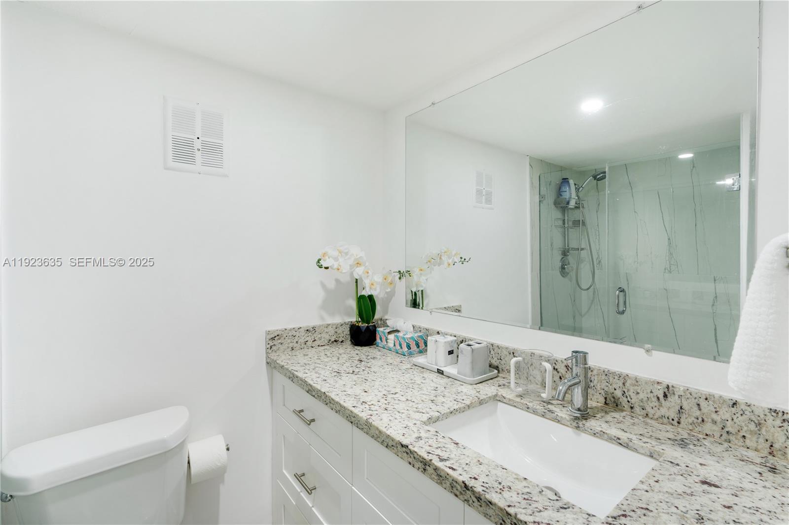 9167 Harding Avenue, Unit 9167 Surfside, FL 33154 - Photo 21 of 45 a bathroom with a granite countertop sink a large mirror and toilet