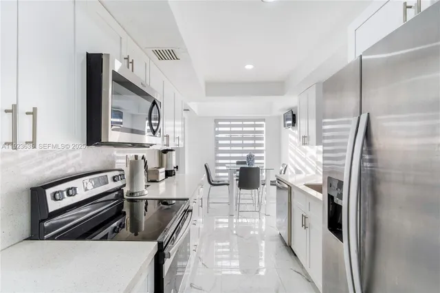 a kitchen with stainless steel appliances granite countertop a refrigerator a stove and a sink