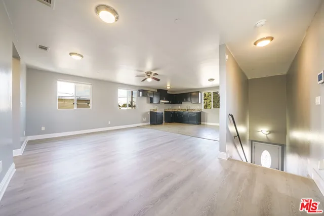 a view of empty room with kitchen and window