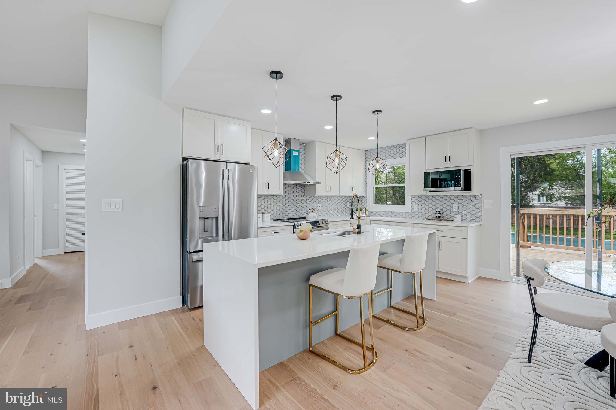 8643 Gateshead Road Alexandria, VA 22309 - Photo 8 of 40 a kitchen with stainless steel appliances a refrigerator a stove a sink dishwasher and a dining table with wooden floor