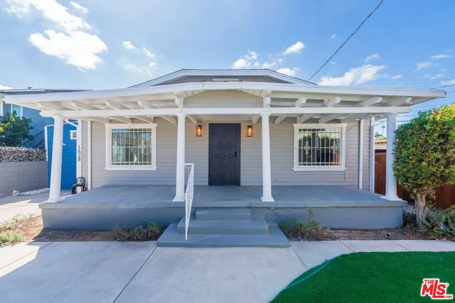 a front view of a house with a yard and potted plants
