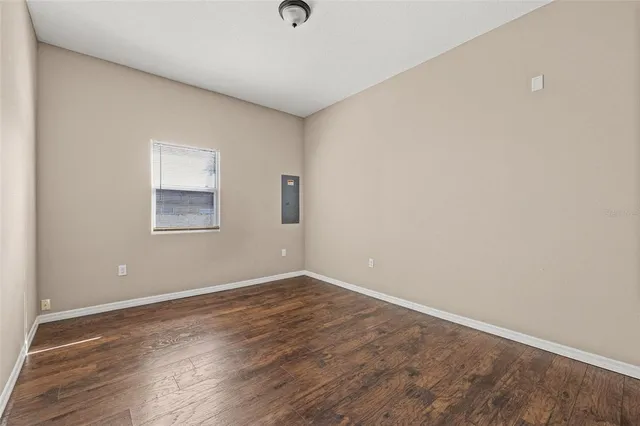 an empty room with wooden floor and windows