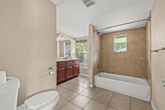 a bathroom with a granite countertop bathtub sink vanity mirror and toilet