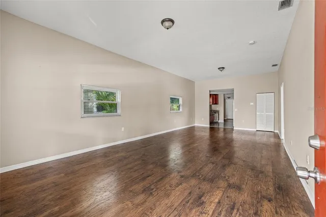 a view of an empty room with wooden floor and a window