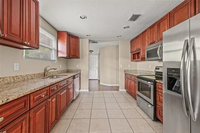 a large kitchen with stainless steel appliances granite countertop a stove a sink dishwasher and a refrigerator