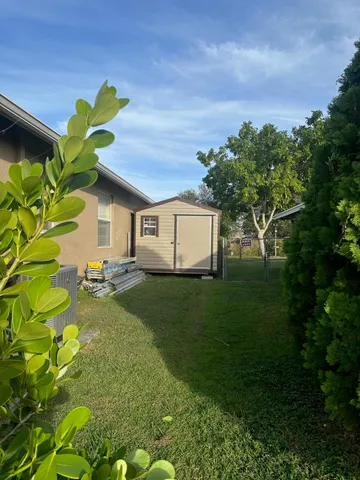 a backyard of a house with plants and large tree