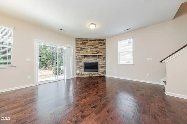 an empty room with wooden floor fireplace and windows