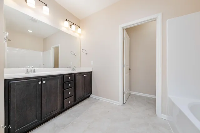 a spacious bathroom with a double vanity sink a large mirror and a bathtub