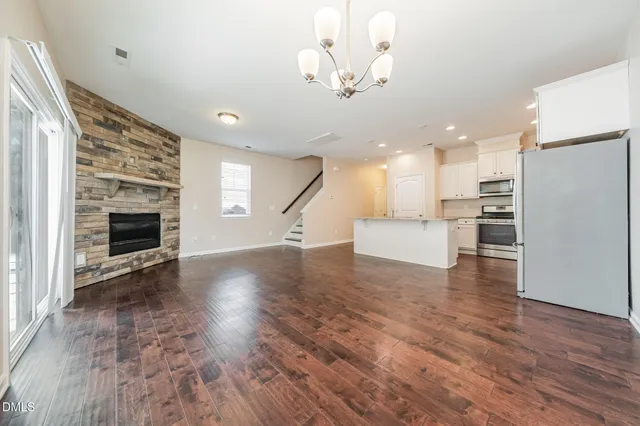 a view of empty room with wooden floor and kitchen view