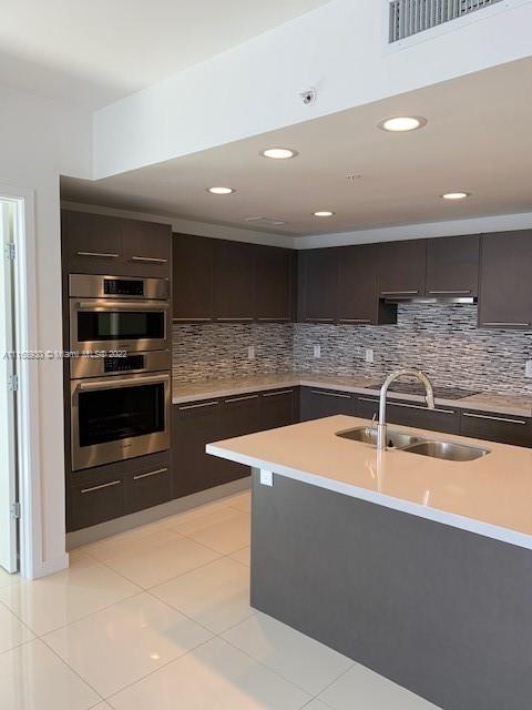 a large kitchen with a sink and stainless steel appliances