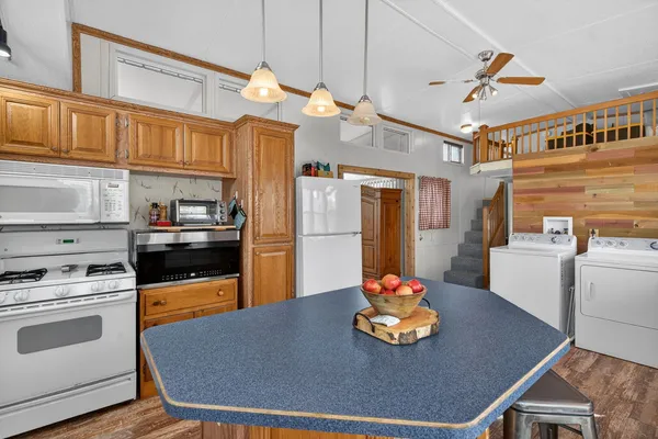 a kitchen with stainless steel appliances granite countertop a sink dishwasher and a refrigerator with wooden floor