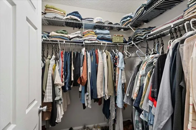 a view of walk in closet with clothes and shoes