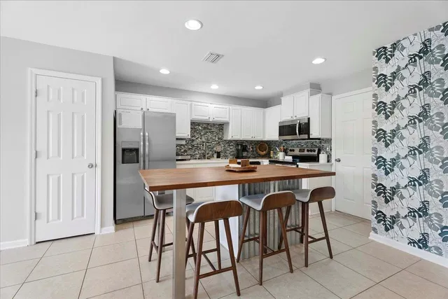 a kitchen with stainless steel appliances granite countertop a table chairs sink and cabinets