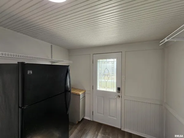 a view of a refrigerator in kitchen and an empty room