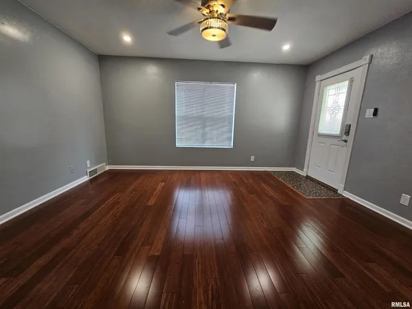 an empty room with wooden floor and windows