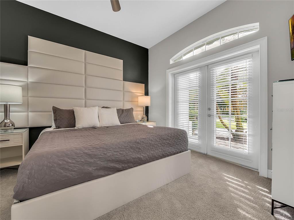 1231 Radiant Street Reunion, FL 34747 - Photo 9 of 26 a spacious bedroom with a bed and glass door