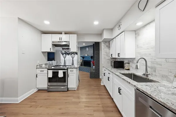 a large kitchen with stainless steel appliances a sink a stove and cabinets