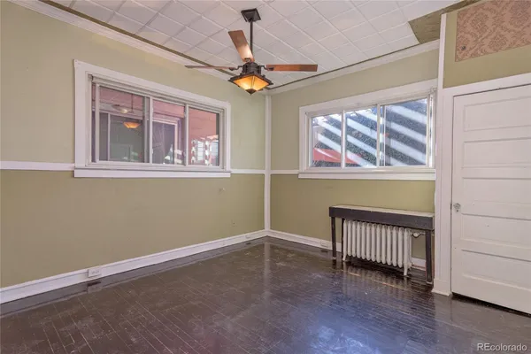 an empty room with wooden floor chandelier and windows