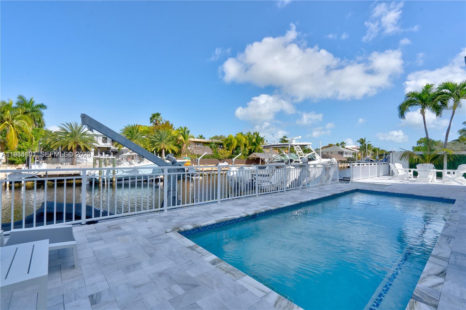 48 Andros Road Key Largo, FL 33037 - Photo 20 of 59 a view of a swimming pool with a lawn chairs and potted plants