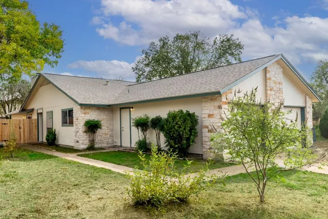 a backyard of a house with potted plants and large tree