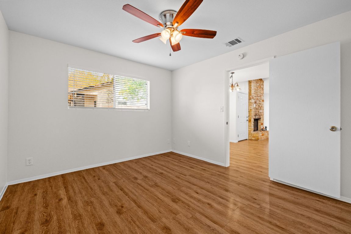 12801 Copper Cliff Avenue, Unit B Austin, TX 78727 - Photo 13 of 23 an empty room with wooden floor chandelier fan and windows