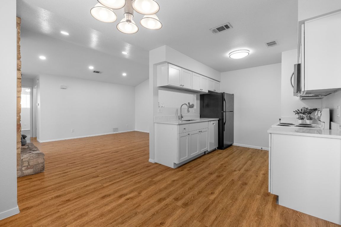 12801 Copper Cliff Avenue, Unit B Austin, TX 78727 - Photo 6 of 23 a kitchen with white cabinets and wooden floor