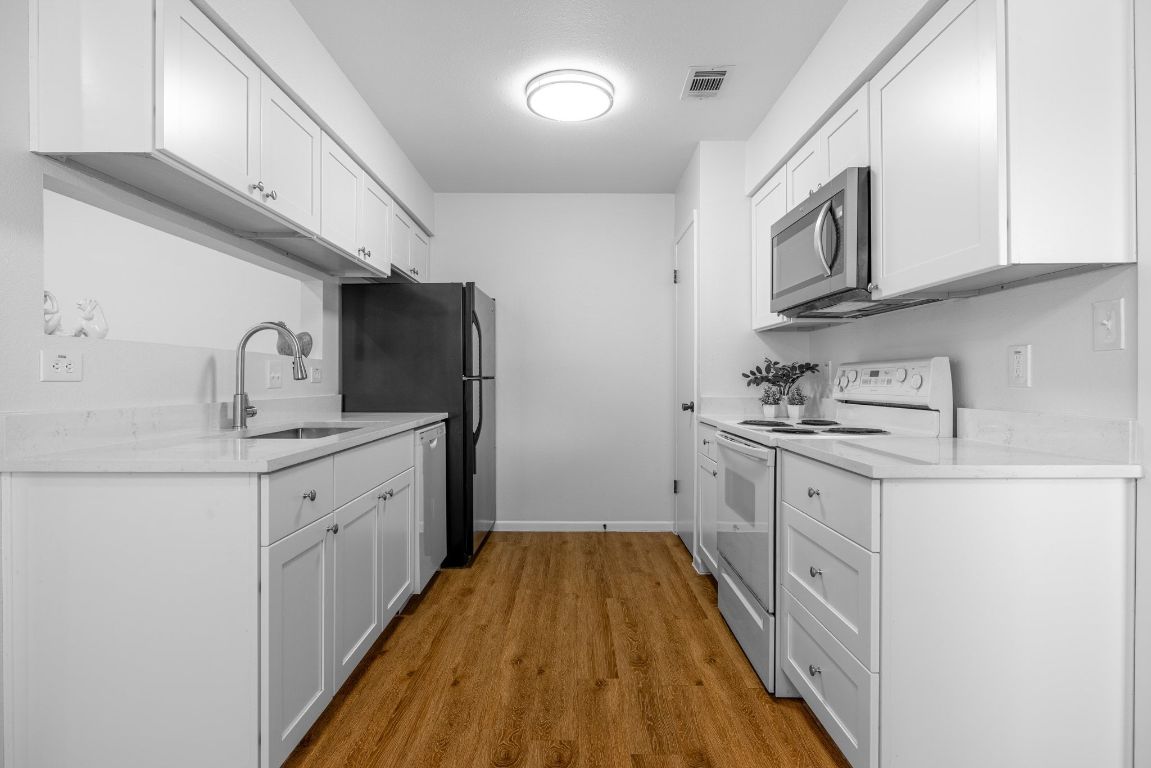 12801 Copper Cliff Avenue, Unit B Austin, TX 78727 - Photo 7 of 23 a kitchen with granite countertop white cabinets and stainless steel appliances