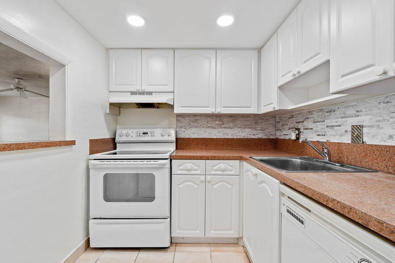 701 Pine Drive, Unit 210 Pompano Beach, FL 33060 - Photo 2 of 20 a kitchen with granite countertop white cabinets and white appliances