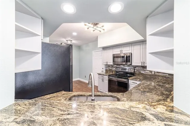 a kitchen with stainless steel appliances granite countertop a stove a sink and a microwave