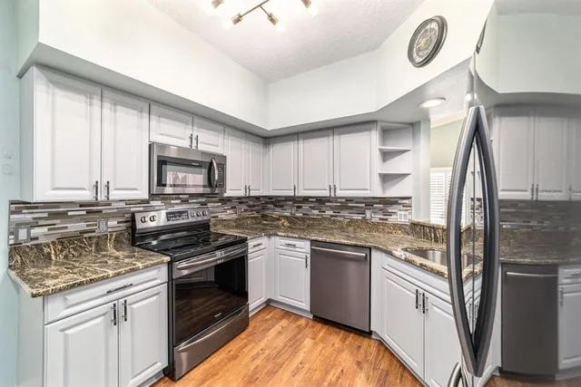 a kitchen with stainless steel appliances granite countertop a refrigerator and a sink